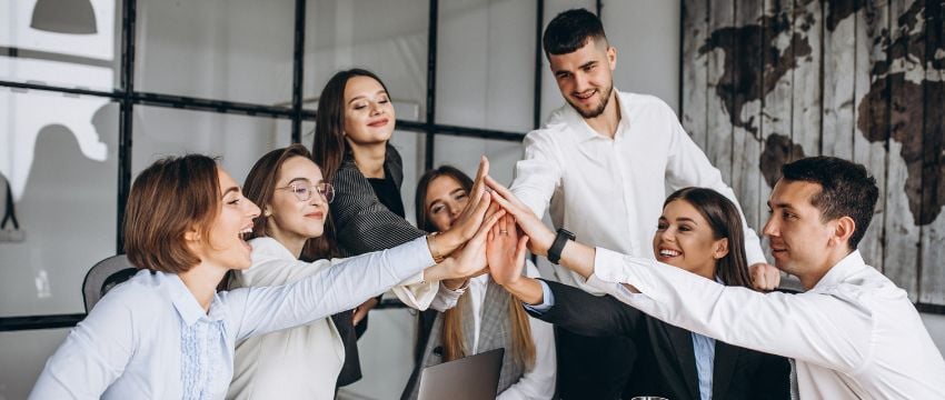 Trabajadores uniendo sus manos en señal de trabajo en equipo en oficinas flexibles