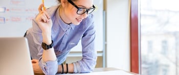 Happy young woman in glasses standing near the window in office and working with blueprint-626551-edited.jpeg