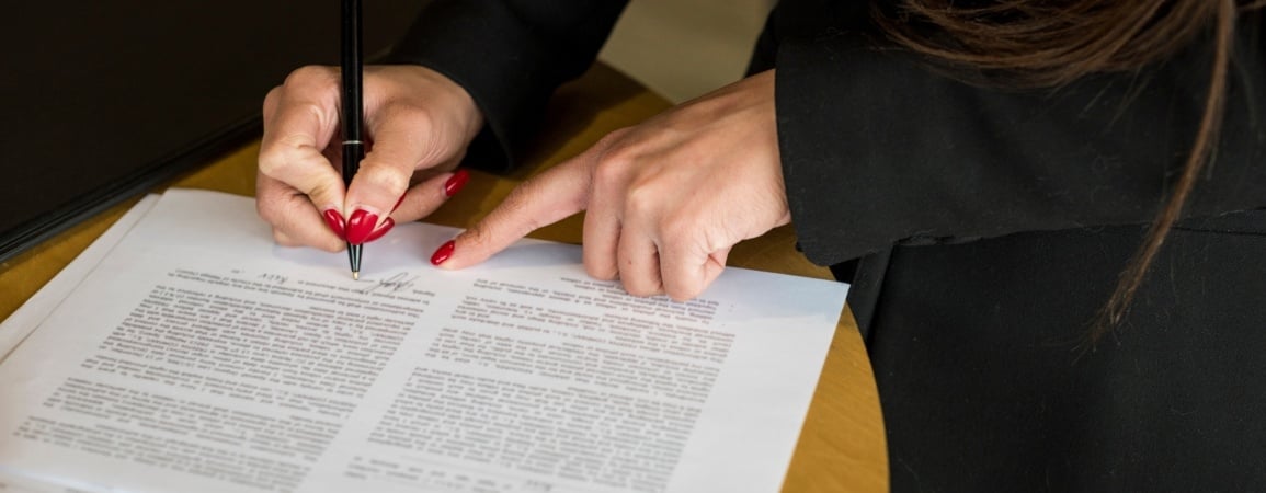 Mujer de negocios escribiendo en el acta constitutiva al iniciar su negocio