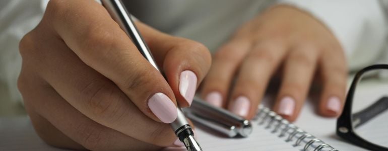 Mujer escribiendo en una libreta formas de analizar a tu competencia con un análisis FODA