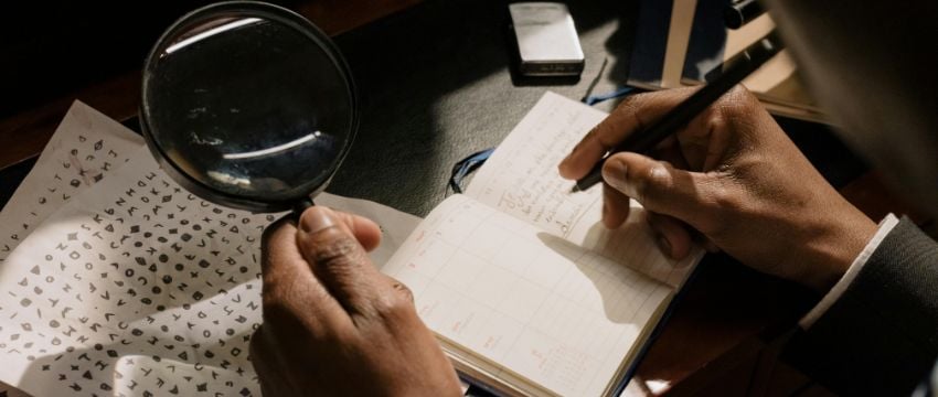 Persona con una lupa y una libreta investigando consejos para analizar a tu competencia