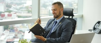 Colaborador leyendo en una libreta y feliz en oficinas IZA de Reforma en CDMX