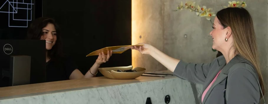 Recepcionista dando documento a colaboradora de IZA en centro de Pabellón M
