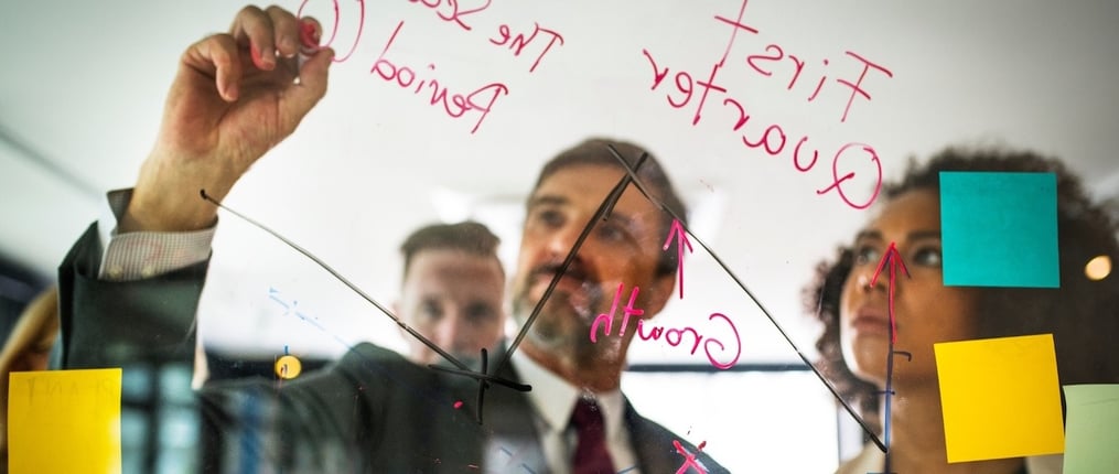 Empresarios escribiendo sobre las 5 fuerzas de Porter en una pared en la oficina