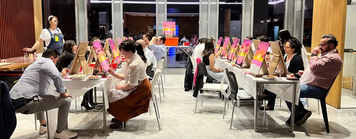 Colaboradores pintando en un taller que impulsa cultura organizacional en un centro de oficinasIZA