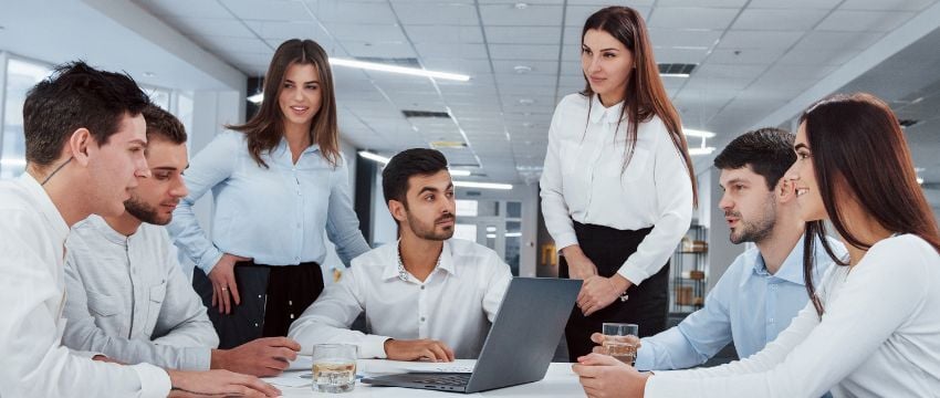 Grupo de personas con aspecto casual formal en una oficina, sentados en una mesa de trabajo discutiendo aspectos de ética empresarial y su importancia e impacto en la productividad