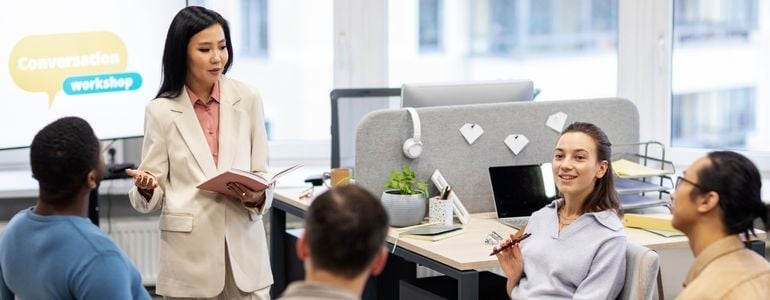 Persona hablando frente a un grupo en un ambiente empresarial, ejerciendo habilidades de comunicación ejecutiva