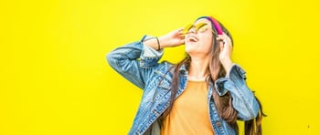 Joven mujer mirando feliz hacia arriba en un fondo amarillo luego de aplicar las claves de la inteligencia emocional