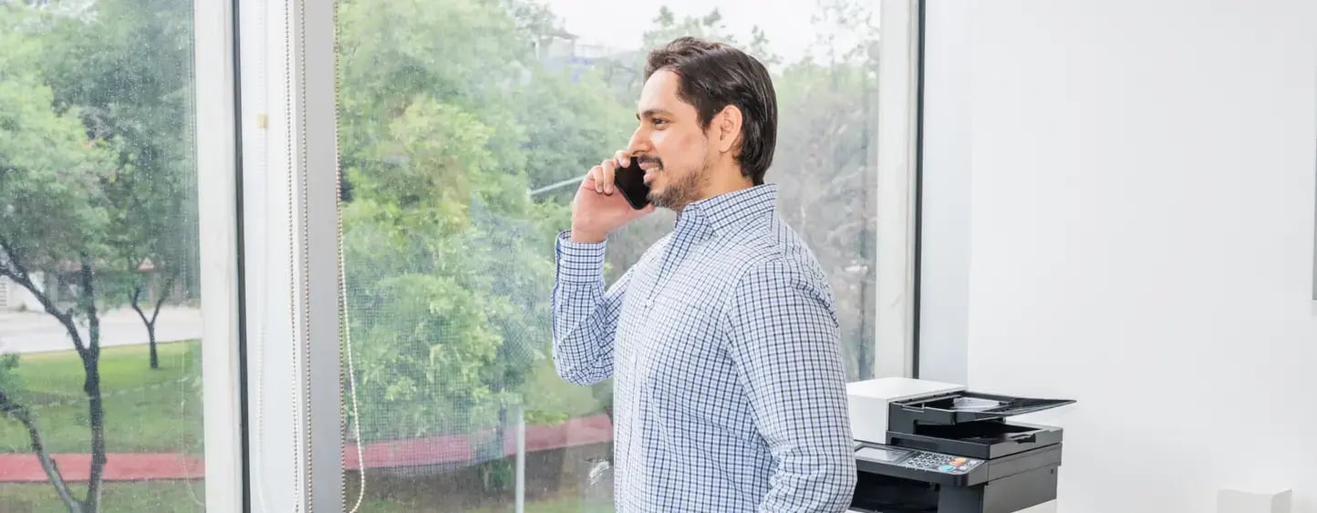 Hombre de negocios viendo a la ventana y hablando por teléfono en oficina IZA BC Calzada San Pedro