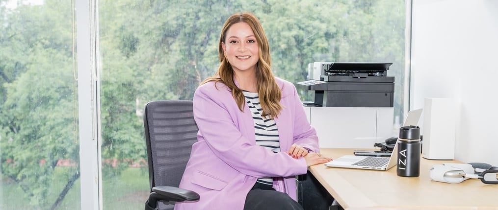 Mujer mexicana feliz en su escritorio de oficina en IZA Business Centers