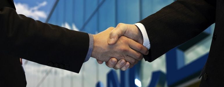 Dos personas de traje estrechando las manos tras hacer networking