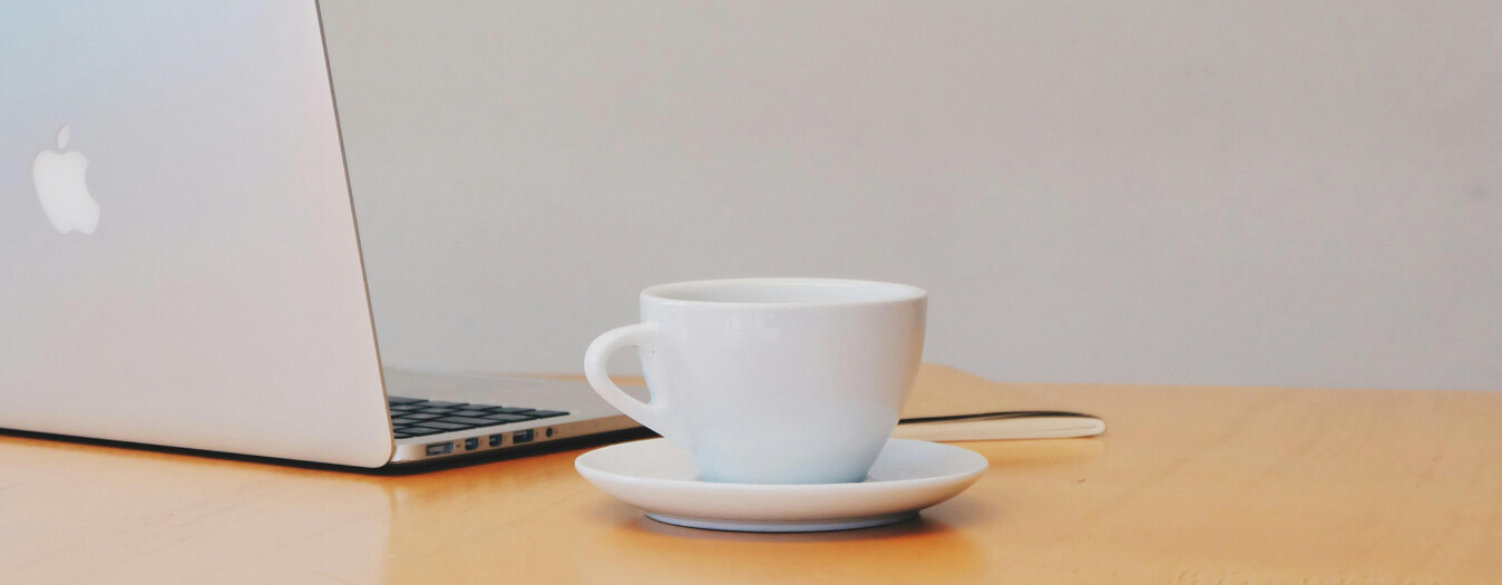 Taza de café y laptop en oficinas IZA de México