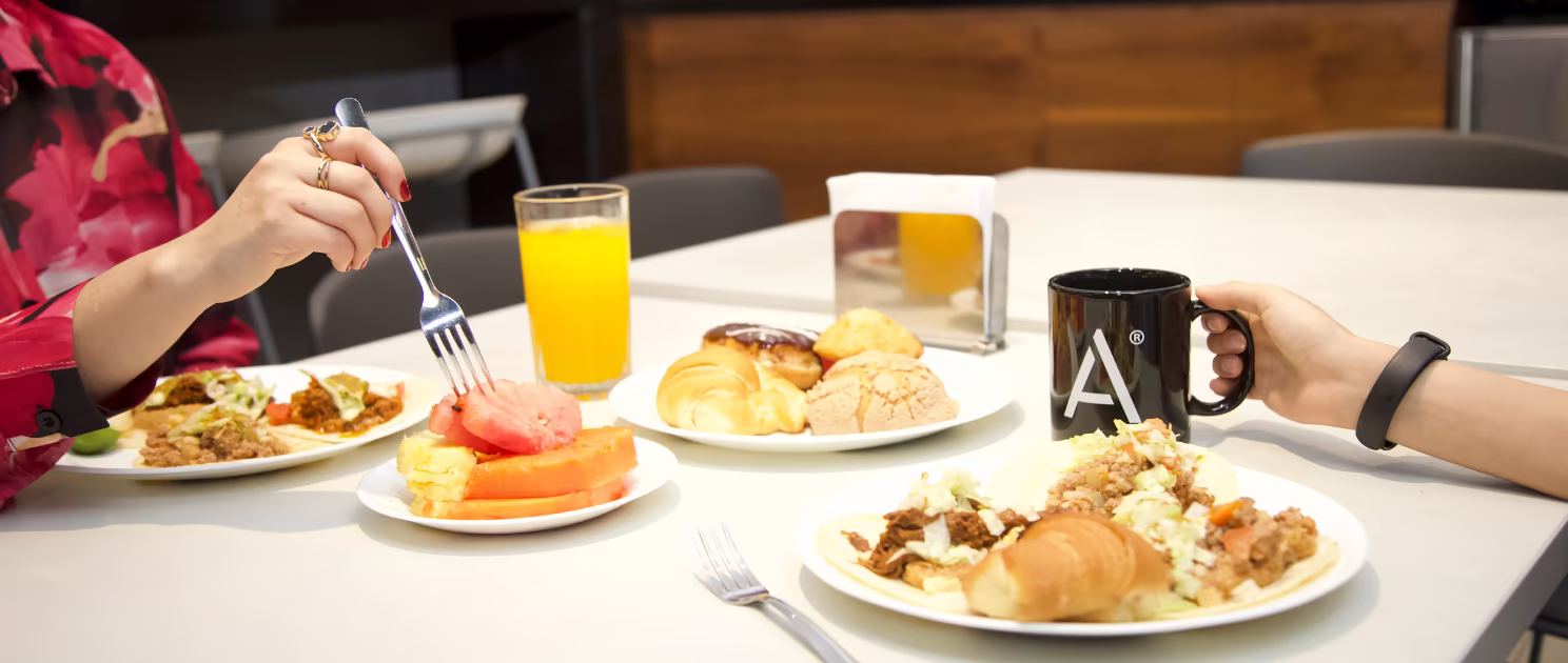 Desayuno de negocios con jugo, fruta, pan y café en IZA