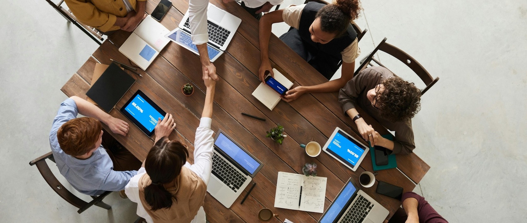 Empleados aplicando las cualidades del trabajo en equipo en un escritorio con sus laptops